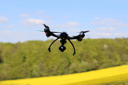 black drone hovering near forest thumbnail