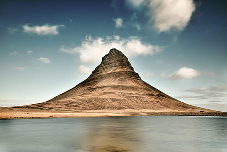 mountain near calm water under blue cloudy sky during daytime thumbnail