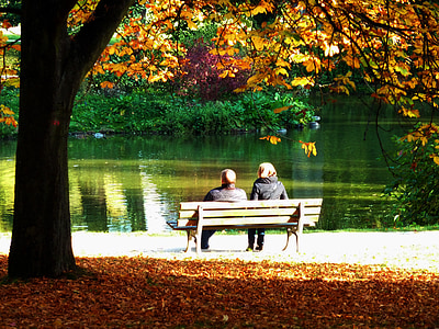 two people sitting on brown outdoor bench thumbnail