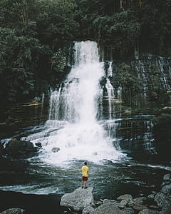 man standing in front of cascading waterfalls thumbnail