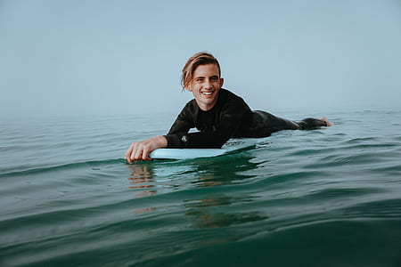 smiling man riding on white surfboard thumbnail