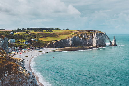 cliff beside ocean under cloudy sky during daytime thumbnail