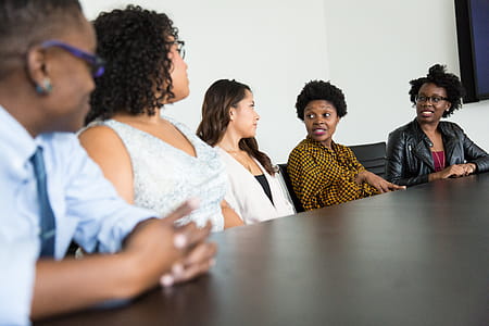 Four Women and One Man Sitting Near Table Inside Room thumbnail