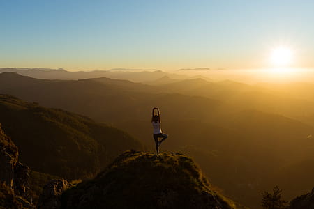 woman meditating on top of mountain under golden hour thumbnail