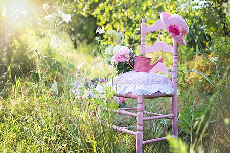 pink wooden armless chair and pink watering can surrounded by green leaf plants at daytime thumbnail