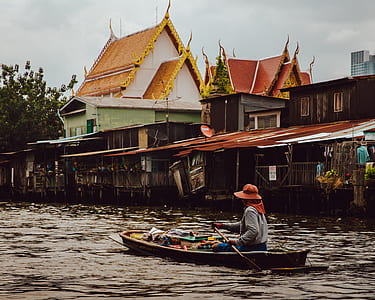 person paddling on boat near houses thumbnail