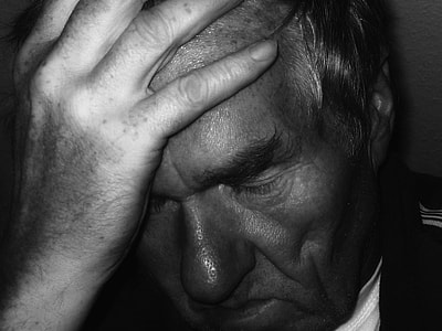 grayscale photo of man holding his forehead thumbnail