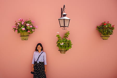 woman standing against orange wall and flowers thumbnail