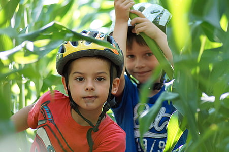 two boys wearing helmet in green corn field during daytime thumbnail