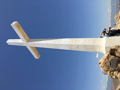 gray concrete cross near body of water thumbnail