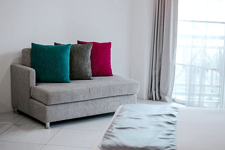 three throw pillows on sofa beside an open window thumbnail