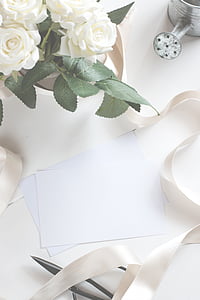 white papers on table beside white petaled flowers thumbnail