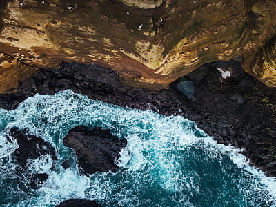 flat lay photography of body of water beside brown mountain thumbnail