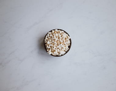 popcorn filled bowl on white surface thumbnail