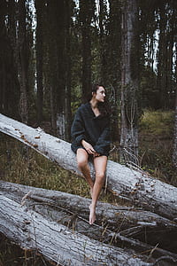 woman wearing black sweater sitting on log while taking picture thumbnail