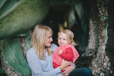 woman carrying girl near brown tree thumbnail