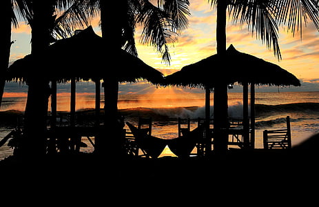 silhouette of hut near seashore at golden hour thumbnail