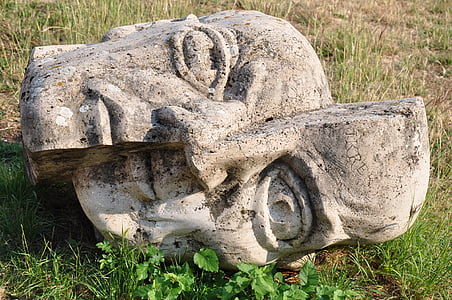 split gray statue head decor on grass thumbnail