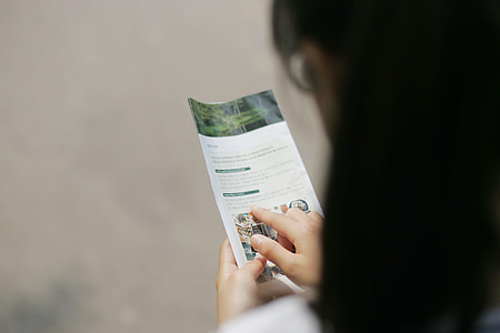 woman with black hair reading catalogue thumbnail