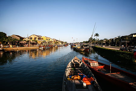 two brown wooden motorboats on body of water between buildings at daytime thumbnail