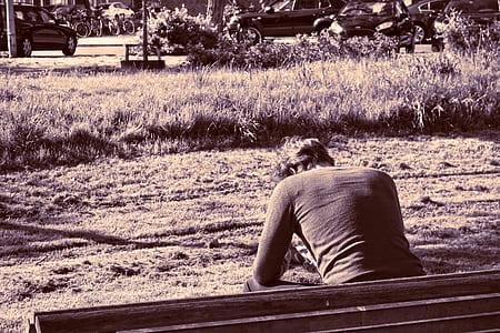 grayscale photography of man sitting on bench thumbnail