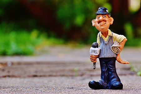 selective focus photography of man holding microphone figurine thumbnail