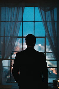 man standing in front of glass window inside room thumbnail