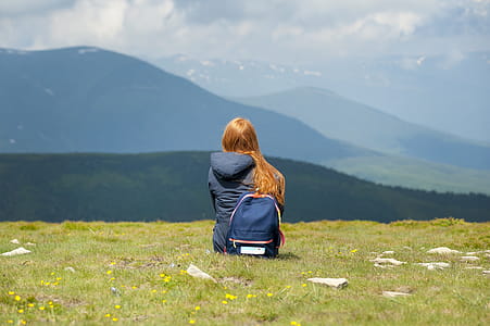 Person Wearing Gray Hooded Jacket Sitting on Grassy Field thumbnail