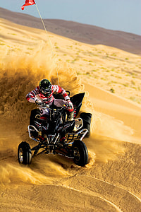 man riding on black ATV on desert sands thumbnail