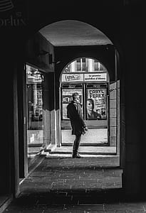 grayscale photography of man standing near poster thumbnail