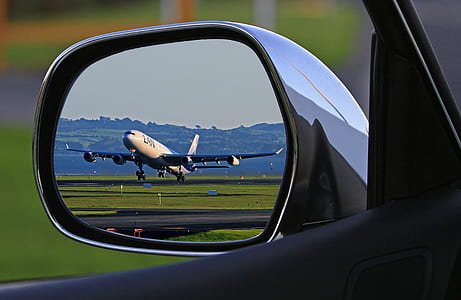 vehicle wing mirror reflect view of airliner about to fly during daytime thumbnail