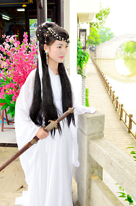 woman in white long dress holding sword standing near water thumbnail