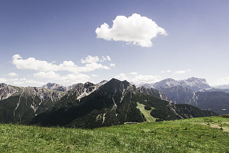 brown mountain near grass field under blue sky at daytime thumbnail