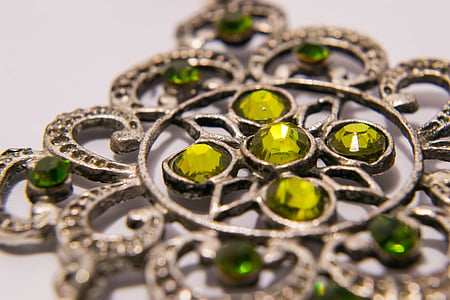 green gemstone encrusted silver-colored accessory on white surface thumbnail