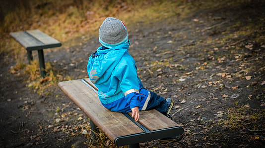 baby in blue jacket sitting on bench thumbnail