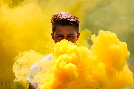 man wearing white top blowing yellow smoke at daytime thumbnail