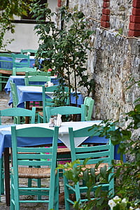 teal and blue wooden tables and chairs beside concrete wall thumbnail