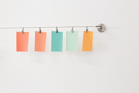 five assorted-color sticky notes hanged on gray wall hooks thumbnail