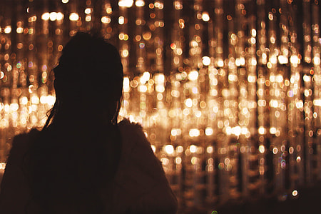 silhouette  photography of woman standing near brown lights thumbnail