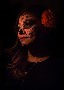 woman with black painted calavera face paint inside dark room thumbnail