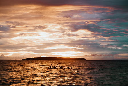 silhouette photo of group of persons raising their hand while floating on body of water thumbnail