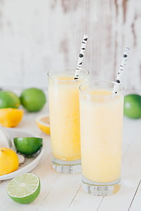 two glasses filled with shakes beside slide lemons on top of table thumbnail