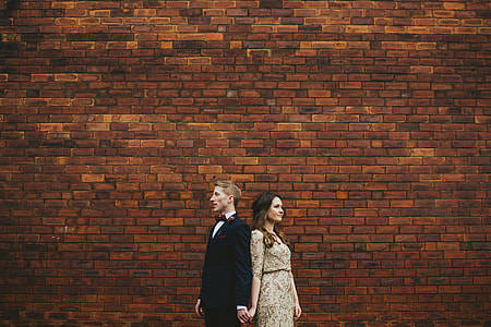 couple standing in front of brown brick wall thumbnail