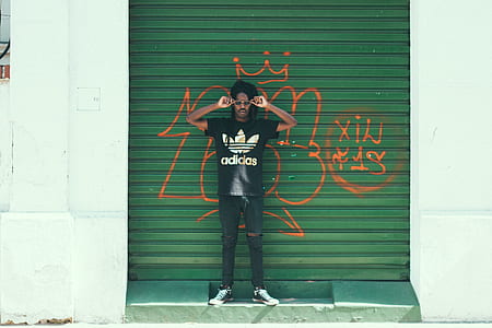 man standing in front of shutter roller with graffiti thumbnail