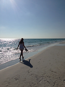 woman holding slippers walking in seashore thumbnail