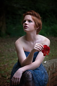 woman holding red flower wearing blue sleeveless dress thumbnail