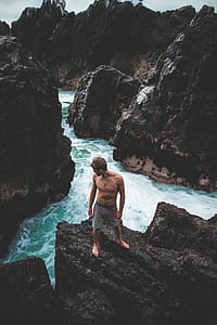 man standing on cliff near seashore thumbnail