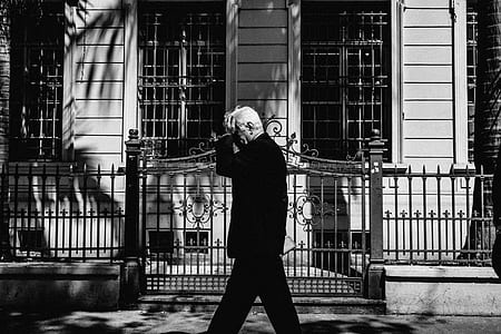 man wearing suit standing near house and gate thumbnail