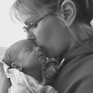 grayscale photo of woman kissing her baby thumbnail