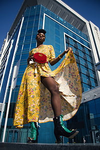 woman wearing yellow floral dress standing near high rise building thumbnail